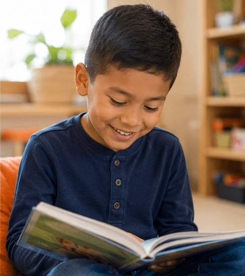 A child smiling while reading a book